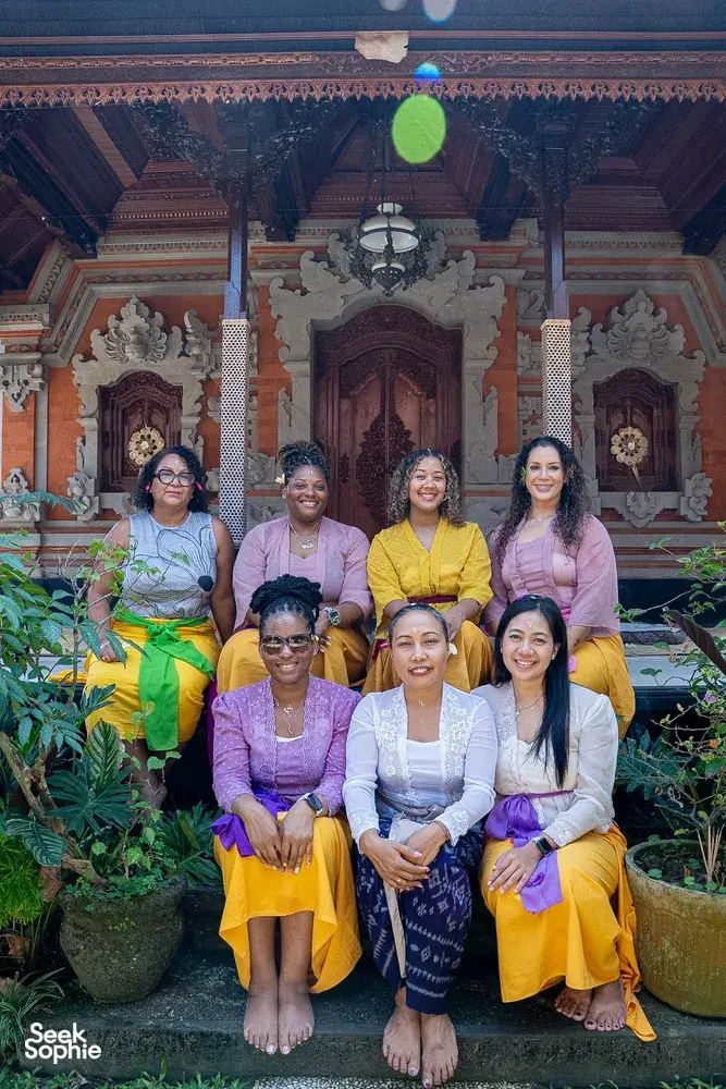 Group of women posing in a Balinese temple courtyard with canang sari offerings during a Ubud, Bali workshop