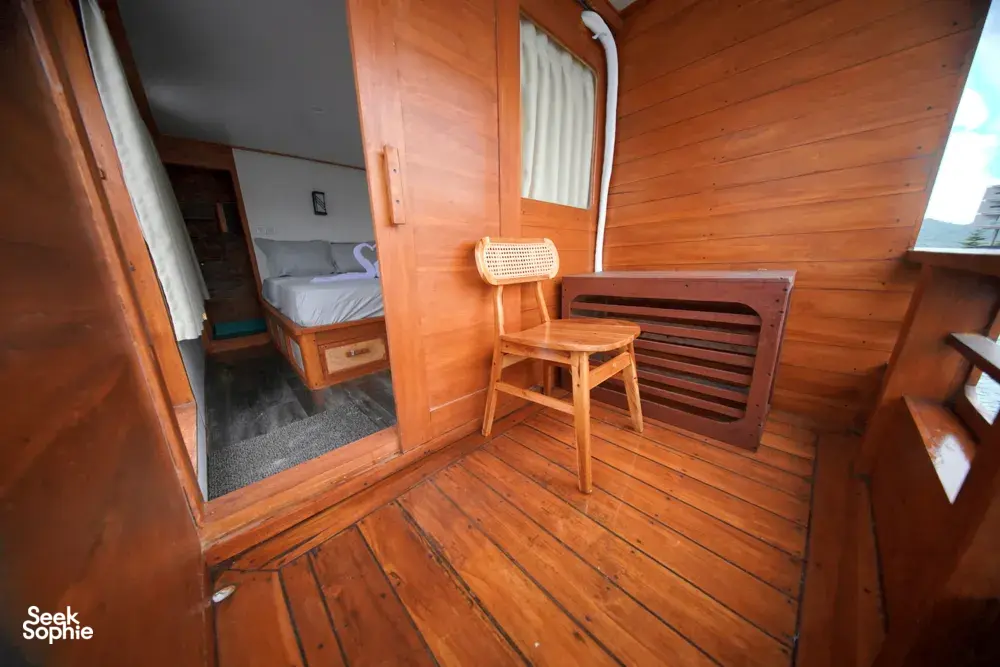 Travass Life 3D2N join-in Komodo trip wooden cabin lounge with a chair, mirror and tucked-away bed, Labuan Bajo