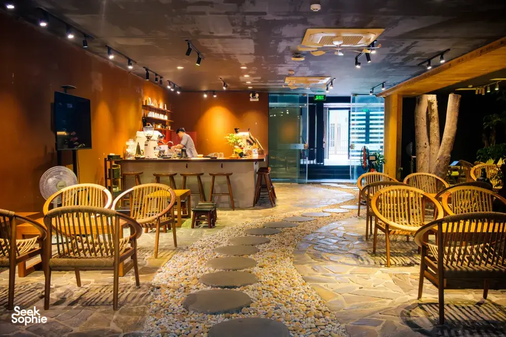 Courtyard café interior used for the Rare Agarwood Tour in Hanoi, with display shelves, a service counter and rows of rattan chairs