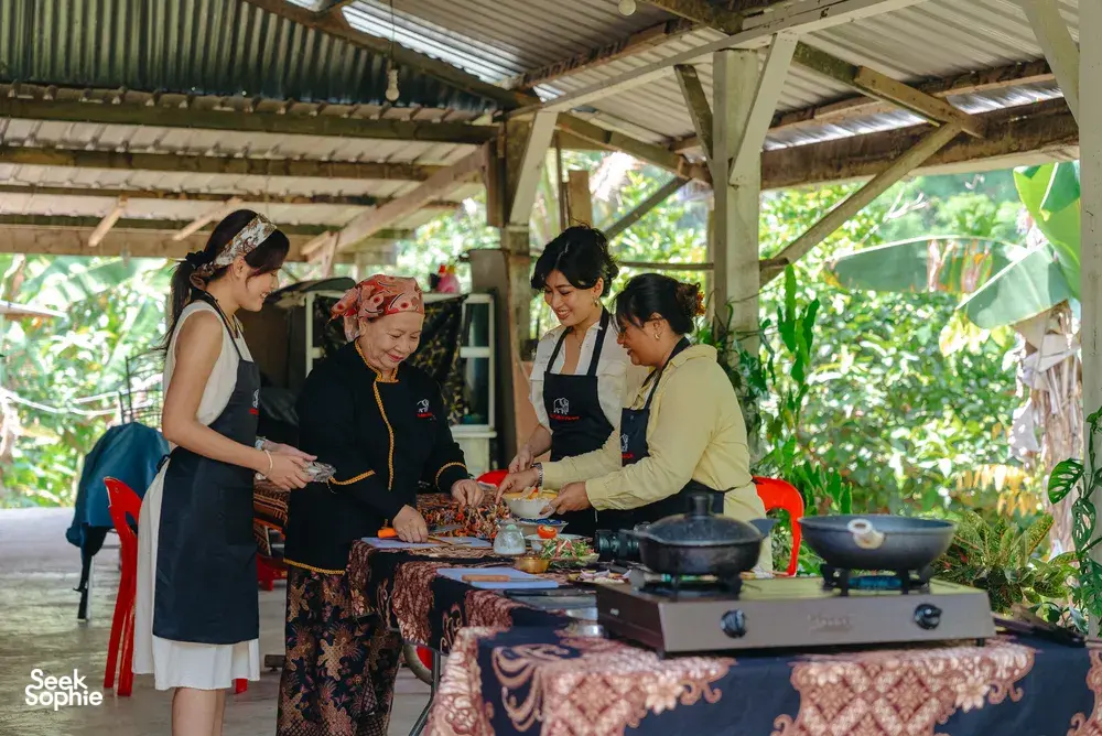 Indigenous Sabahan cooking class with a local family around a wok stove in an open-air kitchen in Kota Kinabalu, Sabah