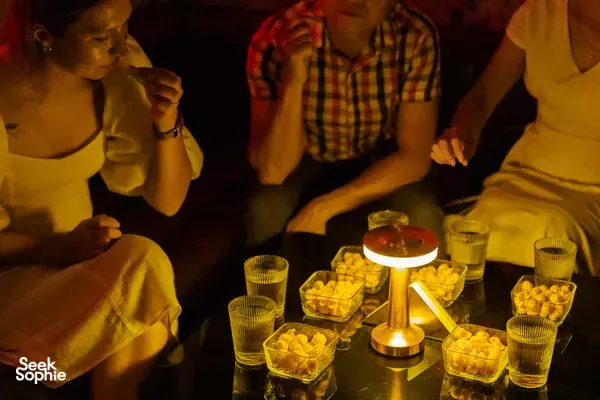 Evening dining in Da Nang with friends chatting around a table of small snack bowls, drinks and candlelight