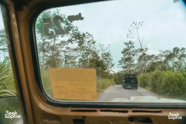 View from inside an Ayla Tour jeep window as another vehicle drives down a road through greenery on Mount Merapi in Yogyakarta
