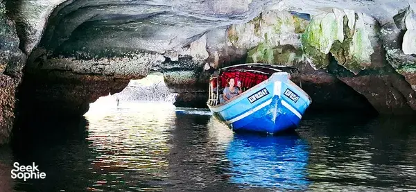 Passengers on a boat glide through a limestone mangrove cave on a sunset cruise in Kilim Geoforest, Langkawi