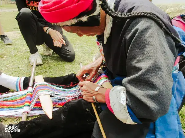 Tibetan artisans’ hands working colourful textiles on a loom during a homestay craft session in Shangri-La