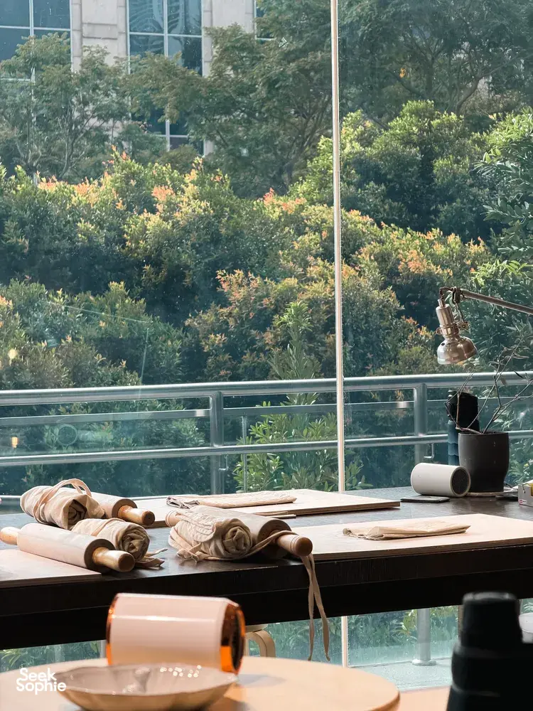 Worktable with pottery clay slabs, rolling tools and a cup by the window in Ina Atelier workshops in Singapore