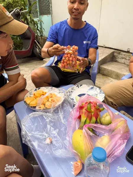 Group sharing bagged fruit at a resting stop in Ho Chi Minh City, enjoying Saigon’s daily life by bike tour