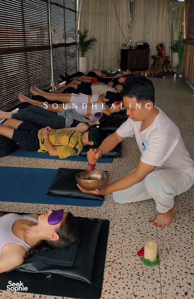 Quiet sound-healing session in a studio in Canggu, with participants lying on mats as a host plays a singing bowl