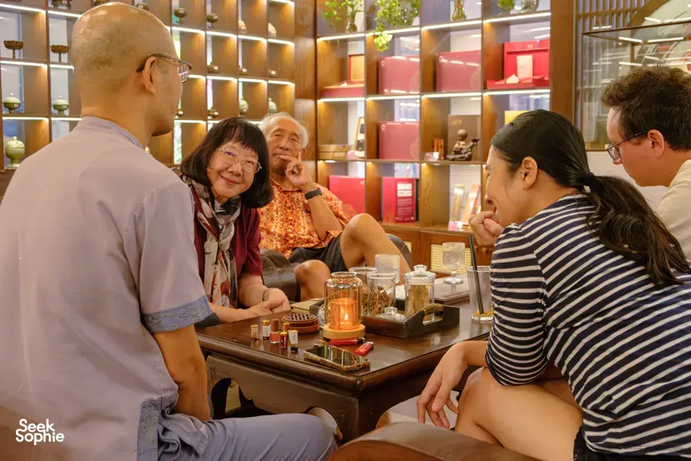 Guests gathered at a tasting counter in Hanoi during the Rare Agarwood Tour, browsing bottles and sample jars with Up Travel Vietnam