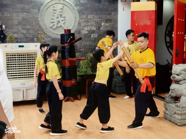 Ho Chi Minh City lion dance troupe practising coordinated stances with tall wooden poles inside a kung fu training room