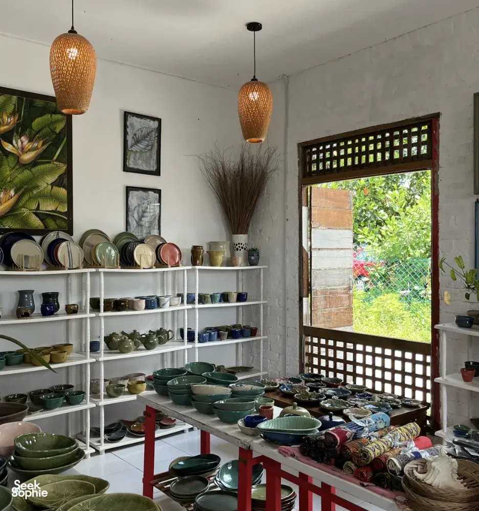 White-walled ceramic room display at Ilham Ceramic Studio in Langkawi, with shelves of bowls and woven pendant lamps