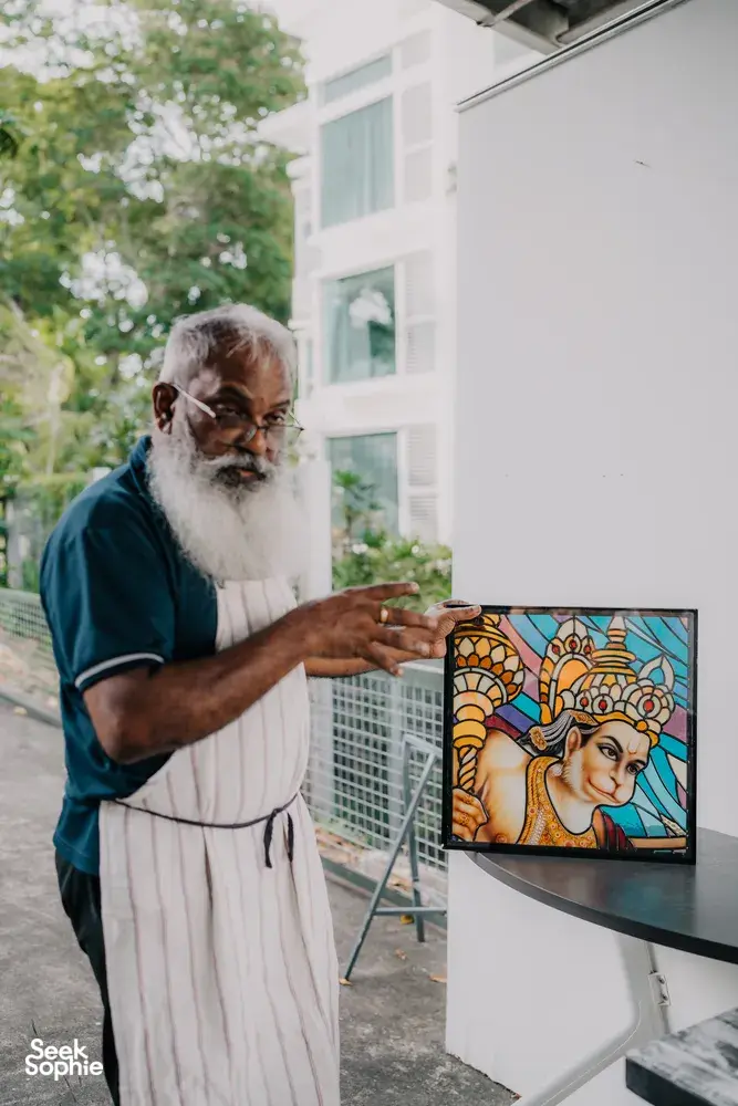 Glass artist at Singapore’s Art Glass Centre standing by a stained-glass panel in an outdoor studio area — workshops in Singapore