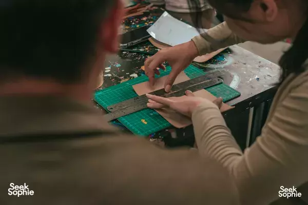 Hands cutting and shaping leather journal pieces on a green cutting mat in a Singapore studio for creative workshops in Singapore