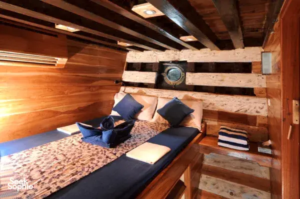Wooden twin cabin with two neatly made beds and stacked towels aboard the Moana Dive 6D5N liveaboard for Komodo Island
