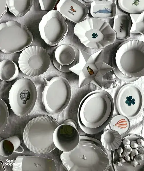 Collection of white ceramic dinnerware in geometric shapes, including star and clover plates, arranged for an editorial-style table