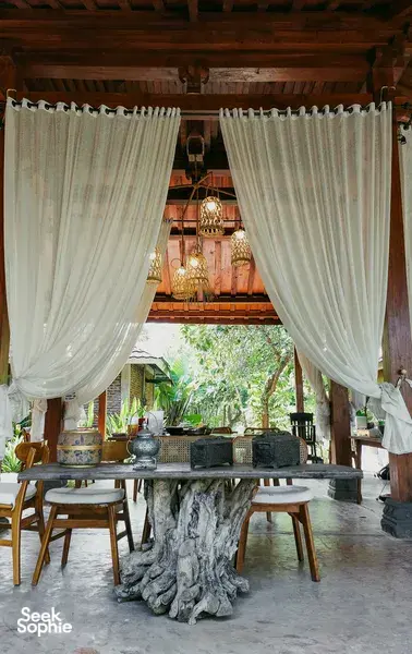 Outdoor tables under hanging lanterns with white curtains at The Kitchen Garden Bajo for Traditional Manggarai vegan cooking, Labuan Bajo