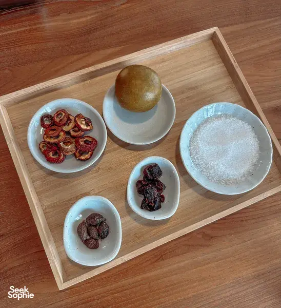 Bowls of dried Chinese-medicine ingredients and powders on a wooden tray for TCM mocktail making workshops in Singapore