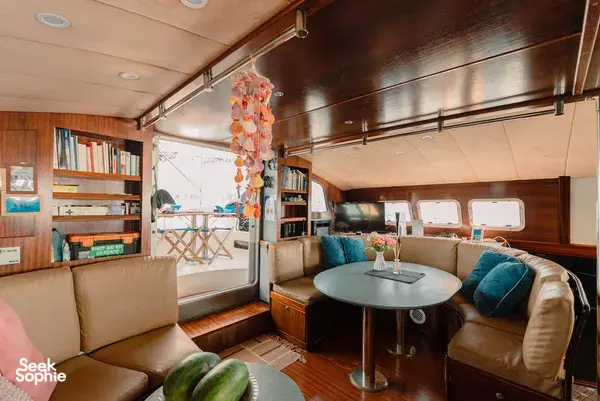 Mawali catamaran lounge in Kota Kinabalu, Sabah, with cushioned seating, a dining table and books for relaxing between stops