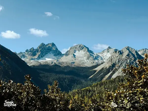 Snow-dusted mountain peaks and rugged ridges rising above forest on the Shangri-La hiking circuit for alpine lakes