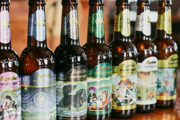 Bottles of craft beer with colourful labels lined up at a brewery counter for tasting in Shangri-La