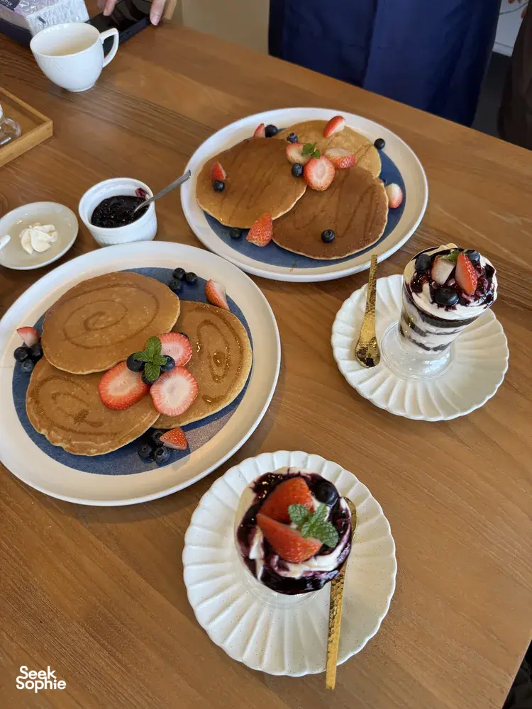 Tumpukan pancake terinspirasi TCM dan cawan pencuci mulut berlapis di meja minum petang yang telah dihidang, bersama The TCM Chef dalam bengkel Food as Medicine di Singapura