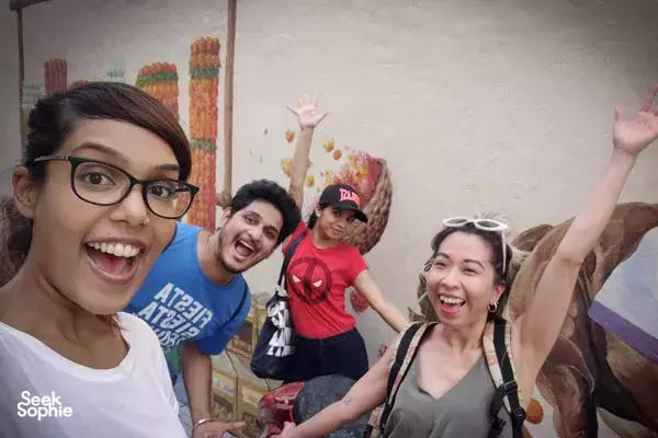 Cheering participants raise hands for a group selfie during an indoor stop on a sustainability scavenger hunt in Singapore
