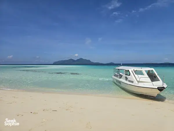 White speedboat resting on a sandy beach in Semporna before snorkel stops on the Bohey Dulang & Islands with Bigfin Divers