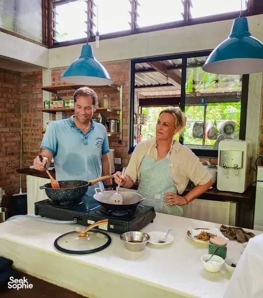 Two people cooking Malaysian comfort food in the stove-lit kitchen at Kebun Lidstari, Langkawi farmhouse