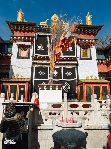 Tibetan Buddhist temple facade in Shangri-La with prayer flags and ornate gateways, bright sky over the courtyard