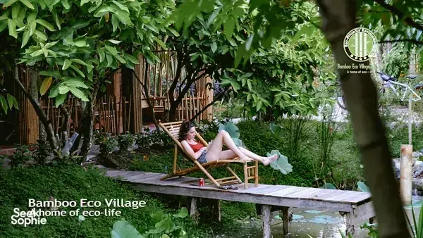 Guest relaxing on a wooden bench at Bamboo Eco Village in Cần Thơ’s Mekong Delta, surrounded by dense green garden leaves