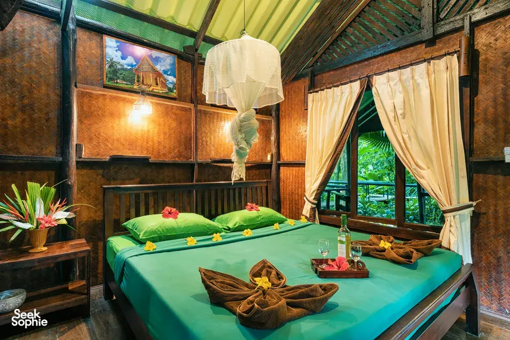 Cozy cabin bedroom with made beds and mosquito netting at Khao Sok Riverside Cottages, family-run cabin stay in Khao Sok National Park