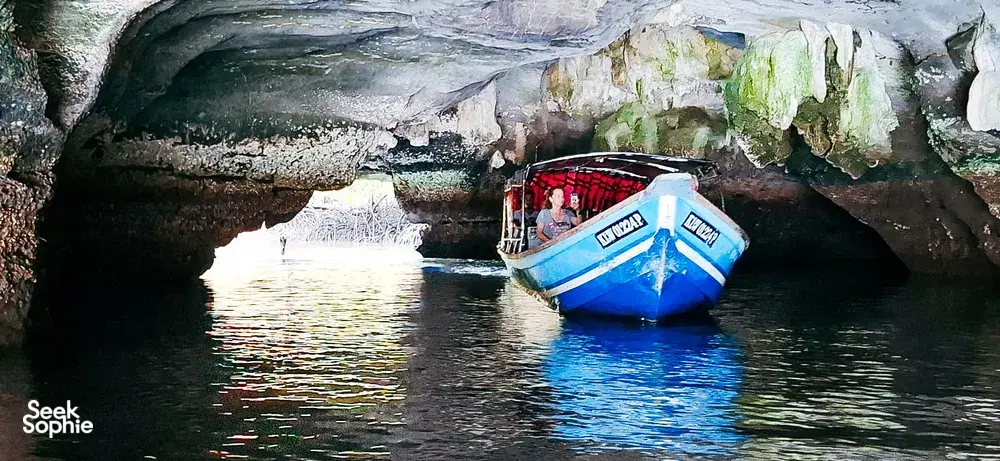 Passengers on a boat glide through a limestone mangrove cave on a sunset cruise in Kilim Geoforest, Langkawi