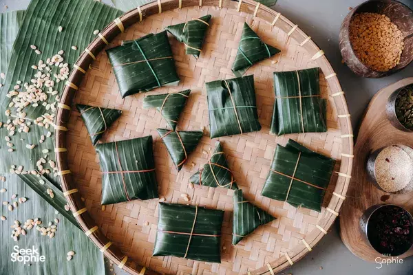 Top-down view of banana-leaf wrapped tempe parcels arranged on a round bamboo tray with soybeans and spices in Bali