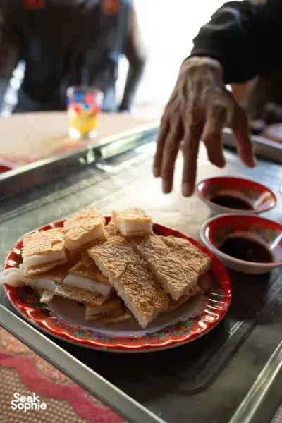 Bánh mì sandwiches with dipping sauce on a red plate, served during a Hoi An food stop with Hoi An Backroad Tours