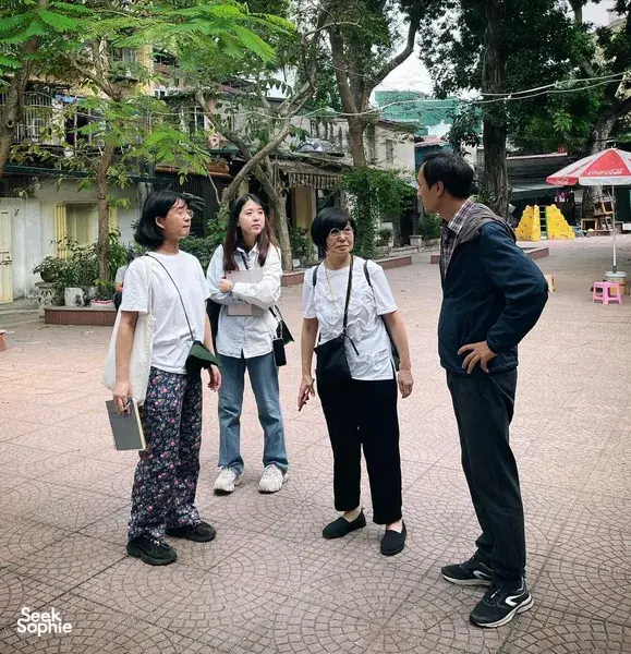 Berjalan dalam kumpulan kecil bersama pemandu tempatan melalui halaman redup di kawasan perumahan kolektif Hanoi, sambil mendengar dan berbual