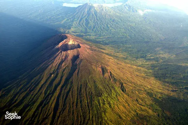 Aerial view of Mount Agung’s rugged ridge and crater at Bali sunrise, with valleys stretching into the distance