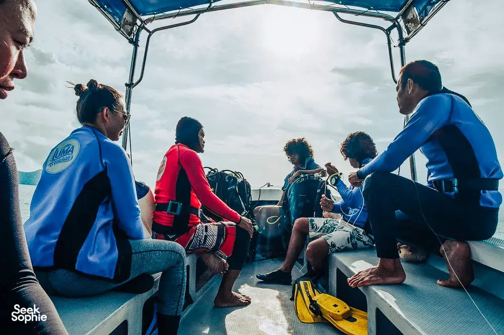 Divers seated on the deck of a dive boat in Semporna, ready with snorkelling and diving gear for a 2D1N stay