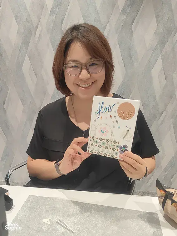 Smiling participant holds her finished vision board for gemstones in Singapore, seated by craft supplies during workshops in Singapore