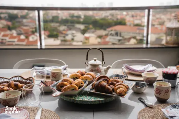 Tray of freshly baked croissants and tea cups on a dining table by a window overlooking Singapore city views