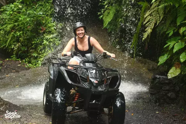 Smiling helmeted rider on a quad bike blasting mud and water along a Bali jungle trail with Gordo Bali Tour near Ubud