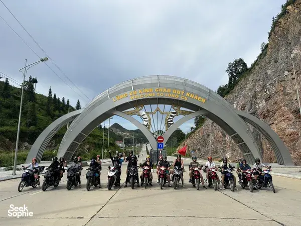 Group of motorbikes and riders lined up at a mountain gateway in Ha Giang, ready for the Ha Giang loop