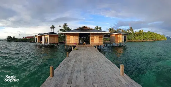 Wooden jetty leading to stilted sea lodge rooms over clear water in Semporna, a base for macro diving stays