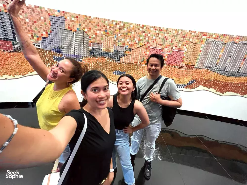Friends pose on a rooftop terrace with a colourful tiled mural wall during a Singapore team challenge — team building Singapore