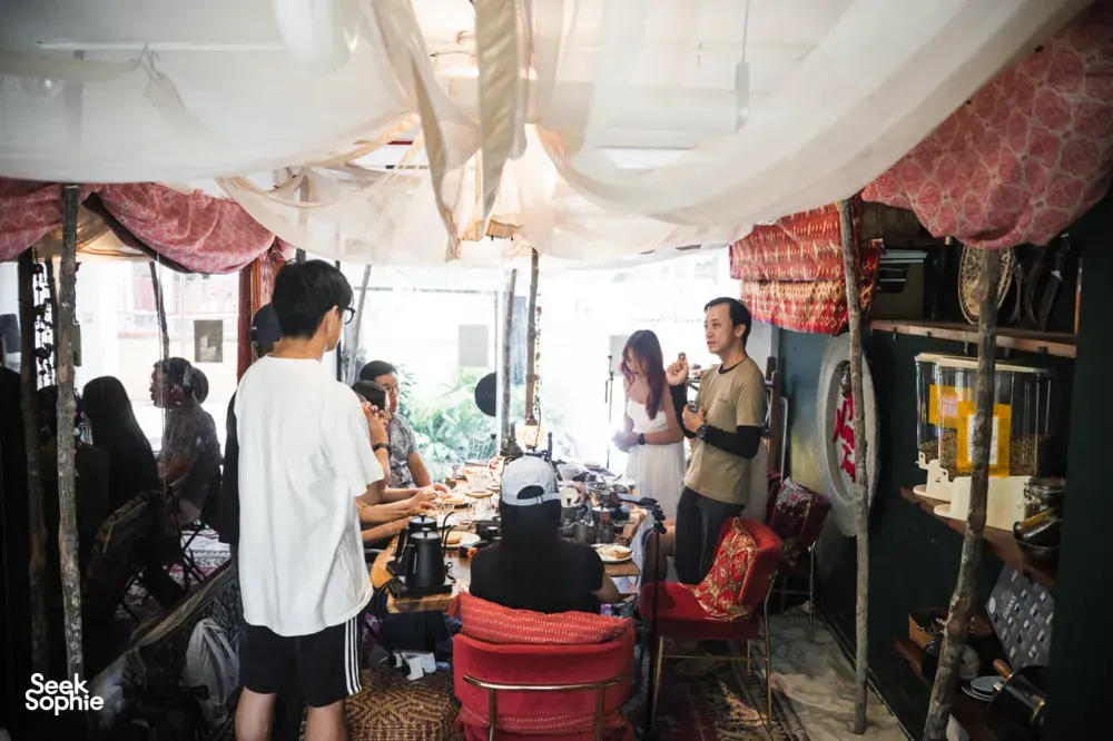 People chatting beside coffee equipment in a cosy tent café during hands-on coffee roasting and bagel brunch workshops in Singapore