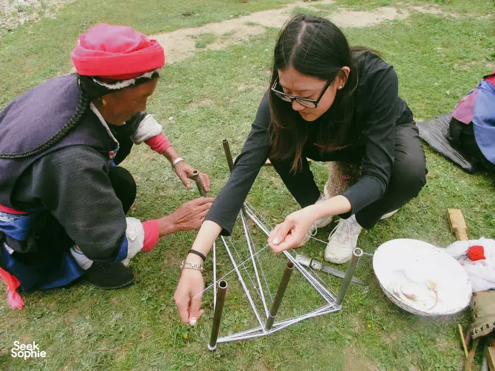 Khampa Caravan-led family homestay craft outdoors in Shangri-La, with two people working at a small table on the lawn