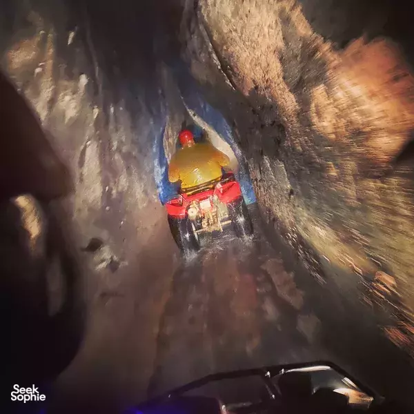 Helmet-cam view from a quad bike as a rider drives through a dusty, muddy jungle passage in Bali