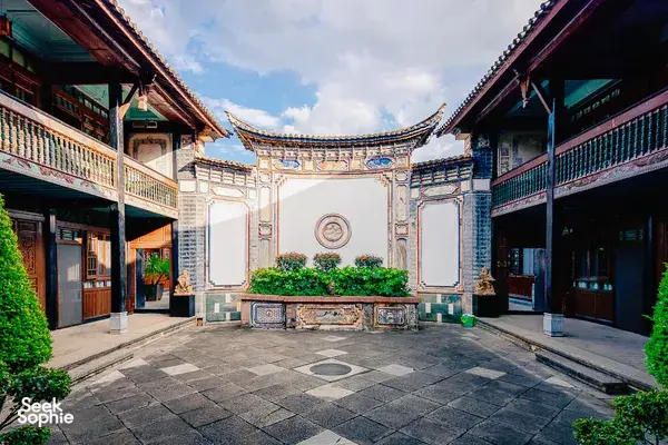 Traditional Bai courtyard gate at Linden Centre in Xizhou Old Town, Dali, framing a stone patio and carved blue-and-white details