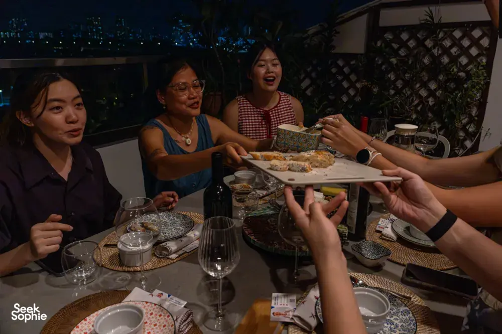 French baguettes and sunset drinks shared around a table in a cosy loft in Singapore at night — date ideas Singapore