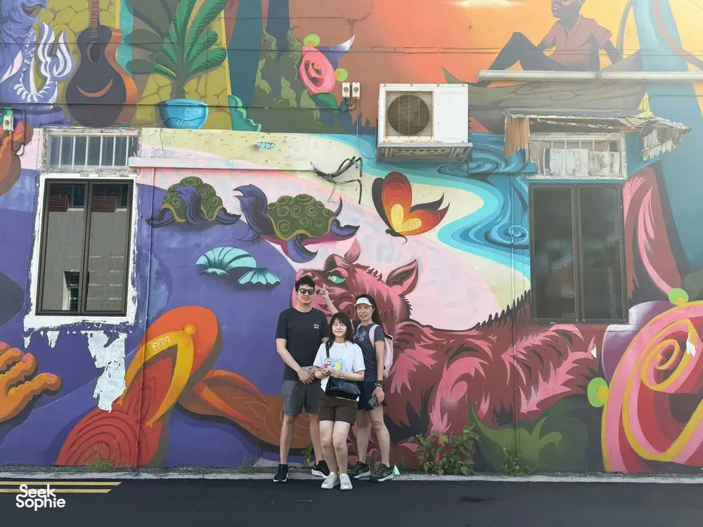 Team members posing in front of a dragon mural in Katong-Joo Chiat on a Monopoly-style team-building trail through Singapore hidden gems.