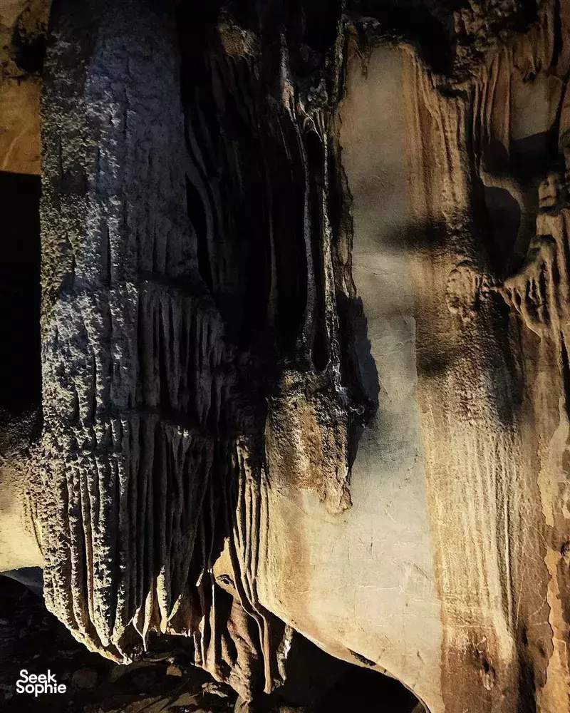 Limestone cave chamber on a Lyra Cruise Collection 4D3N luxury Halong Bay cruise, with stalactites and an illuminated passage