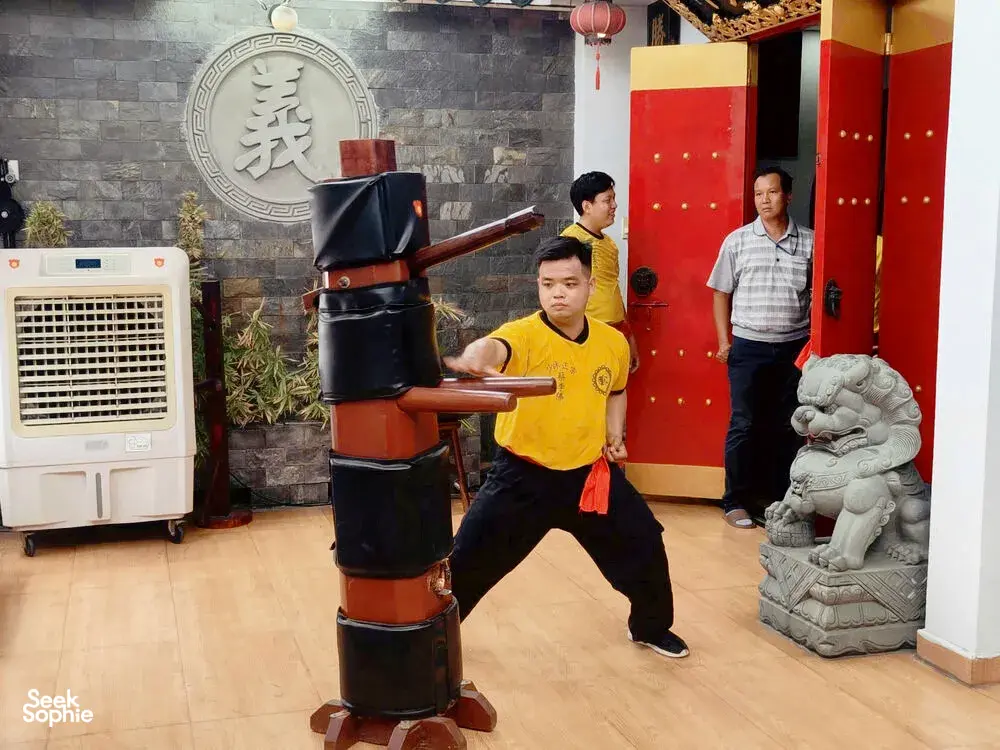 Kung fu and lion dance practice in a Ho Chi Minh City studio, learners working around a black-and-red wooden training dummy